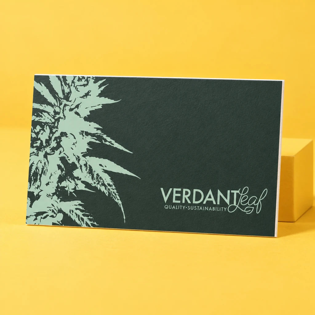 A single Verdant Leaf business card with pale green branding on a warm yellow studio backdrop.